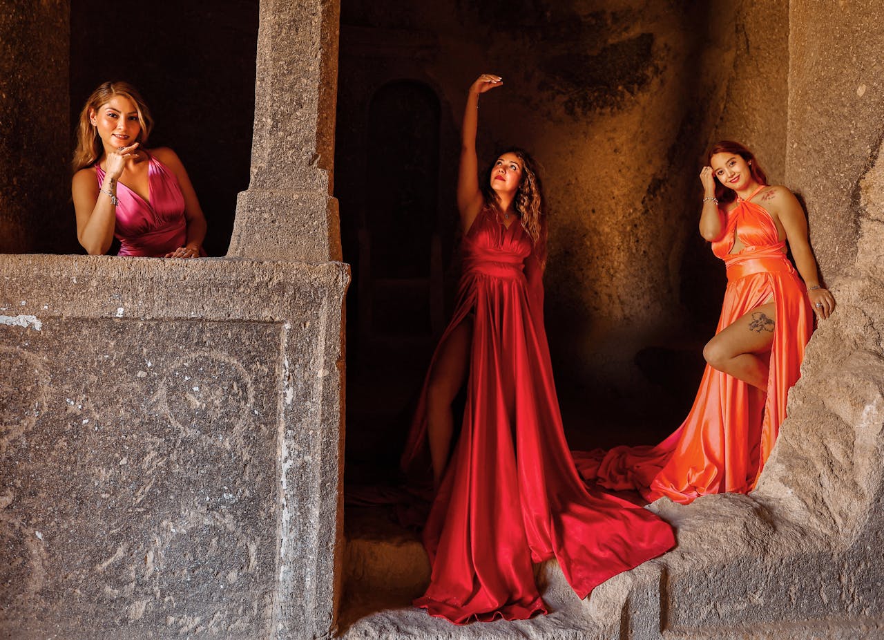 Elegant women in colorful dresses posing in an ancient cave in Cappadocia, Turkey.