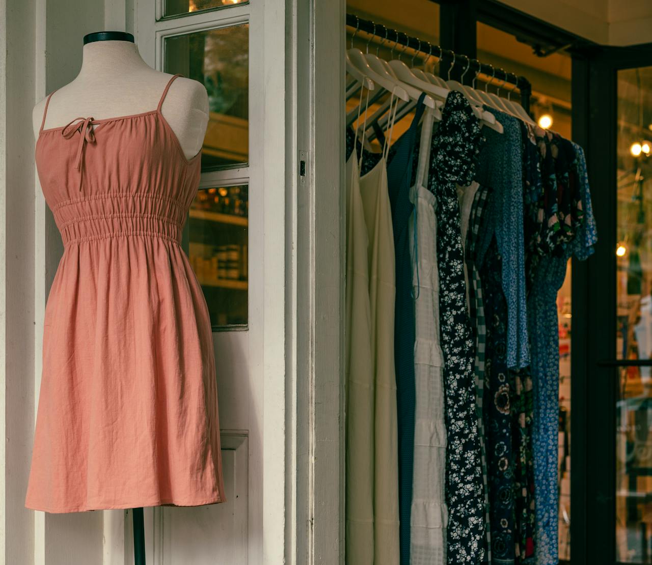 About Mannequin with a pink dress and clothing rack in a stylish boutique.